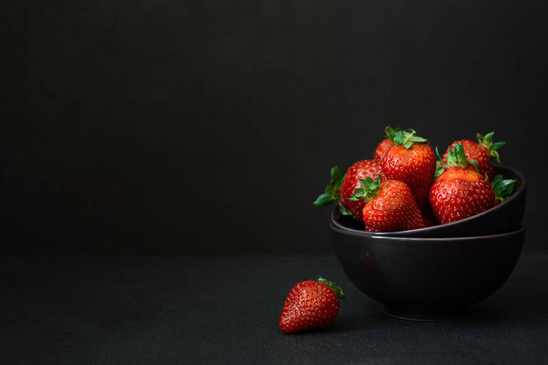 Fresh ripe strawberries in bowl on dark background. Copy space - Фото, зображення
