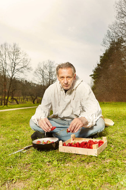 Natural older man in dirty white shirt preparing strawberry fruit lunch - Фото, изображение
