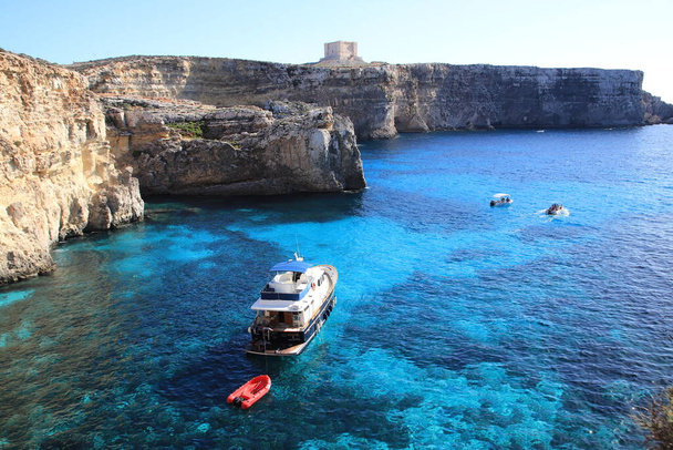 Cominon saari, Malta - 20. lokakuuta 2020: Veneet turistien kanssa, näkymä kalliolta Cristalin laguunille. - Valokuva, kuva
