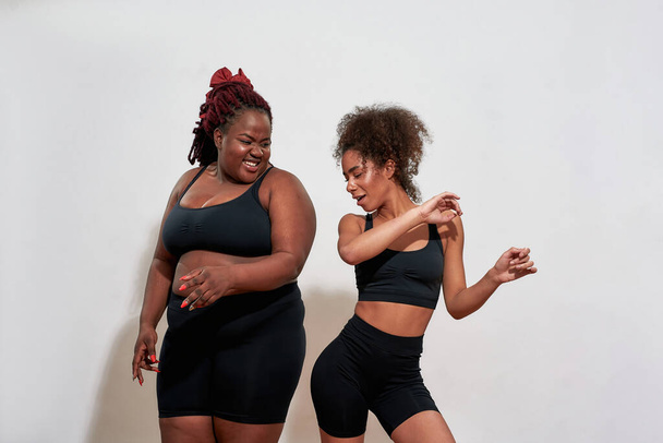 Couple of black women hitting with their hips, joyful mood  - Zdjęcie, obraz