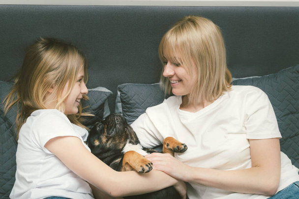 Mom and daughter lie in bed with their French Bulldog dog - Valokuva, kuva