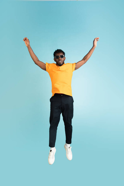 Full length portrait of African young man isolated over blue studio background with copyspace - Foto, afbeelding