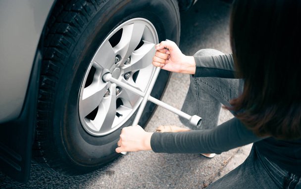 Woman using a wrench, which is a device for changing tires Pickup truck On the road alone, to strong woman and transportation concept. - Φωτογραφία, εικόνα