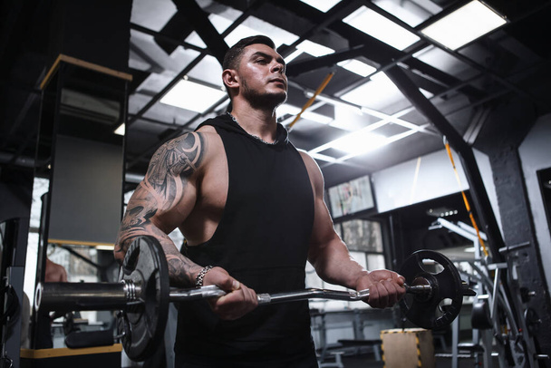 Χαμηλή γωνία βολή ενός bodybuilder τατουάζ με σκισμένο σώμα άσκηση με barbell - Φωτογραφία, εικόνα