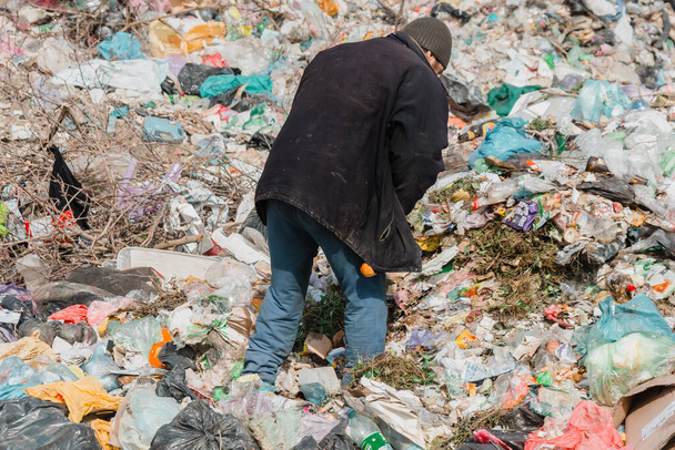 Ucrania, Tatarbunar - 13.04.2021: Un hombre recoge basura en el vertedero de la ciudad. Volcado de la ciudad. - Foto, imagen