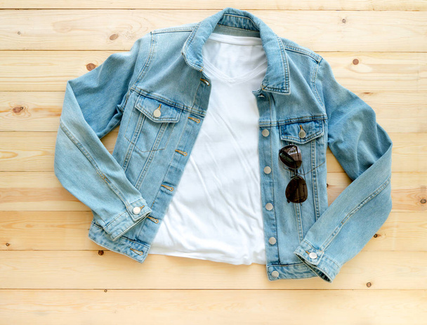 White tshirt mockup and denim jacket jeans on brown wooden background. Template, flat lay - Photo, Image