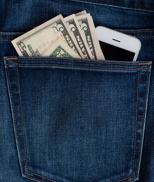 billetes de teléfono móvil y dólar en el bolsillo de los vaqueros.  - Foto, imagen