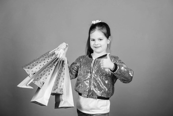 Girl with shopping bags violet background. Shopping and purchase. Black friday. Sale discount. Shopping day. Child hold bunch packages. Kids fashion. Surprise gift. Great stores. Great choices - Photo, image