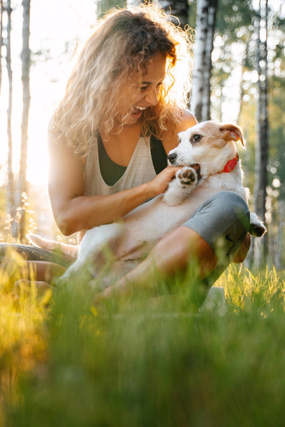 Woman with curly hair plays with dog jack russell in the park. - Foto, Bild