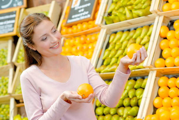 a girl is comparing oranges - Фото, зображення