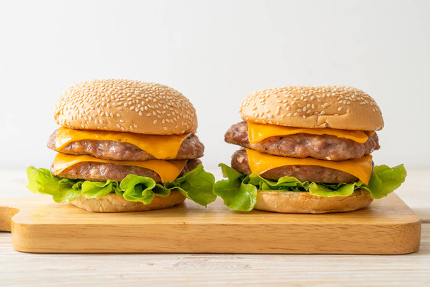 pork hamburger or pork burger with cheese on wooden board - Foto, afbeelding