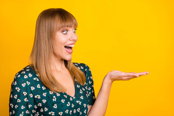 Photo of young woman excited surprised sale demonstrate product ad offer look empty space isolated over yellow color background - 写真・画像