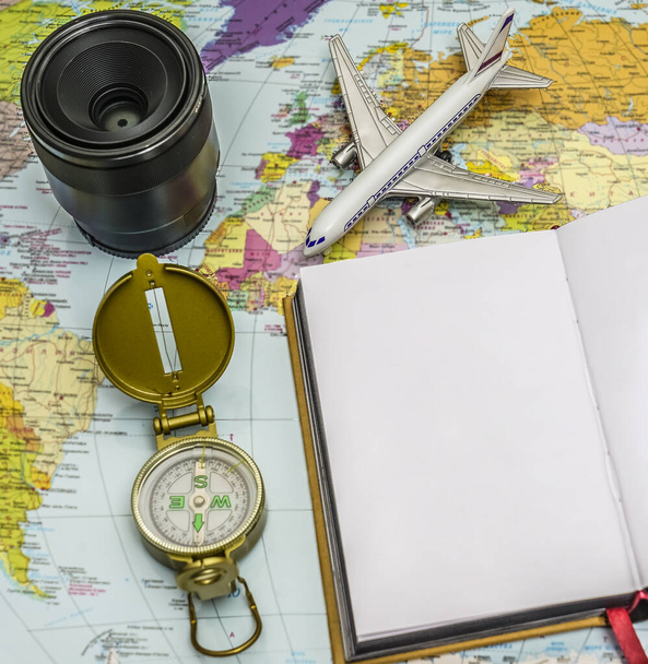 Travel background concept. objective with plane and compass,  empty white paper for text. world map on background. - Φωτογραφία, εικόνα