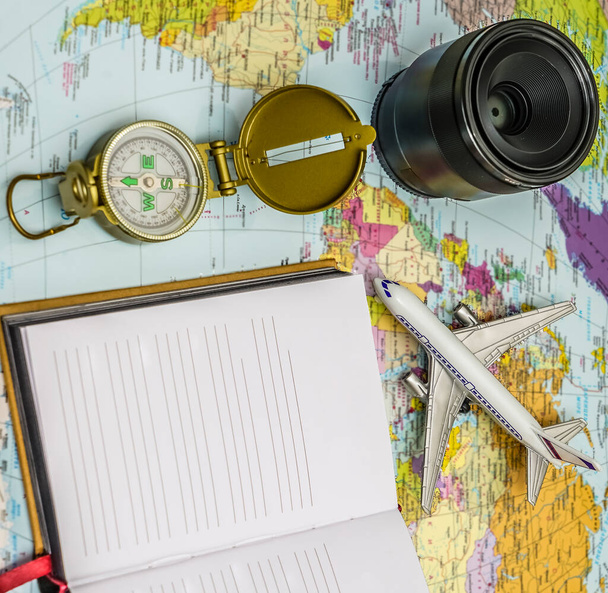Travel background concept. objective with plane and compass,  empty white paper for text. world map on background. - Photo, Image