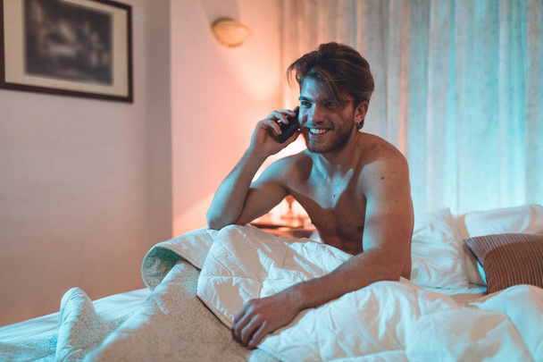 Retrato de homem jovem usando telefone em mau interior em casa  - Foto, Imagem