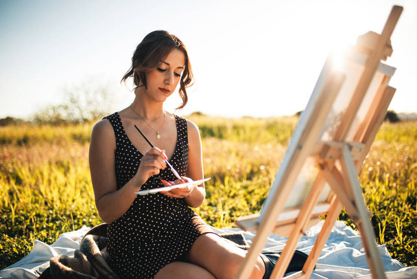 Retrato de belleza joven pintura sobre lienzo en campo de flores al atardecer  - Foto, Imagen