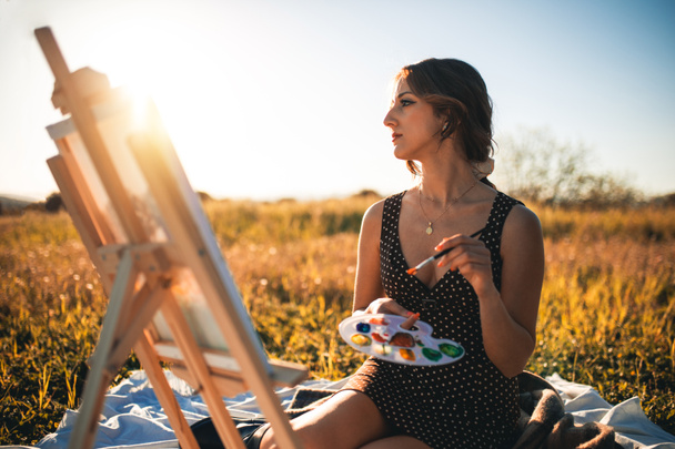 Retrato de belleza joven pintura sobre lienzo en campo de flores al atardecer  - Foto, Imagen