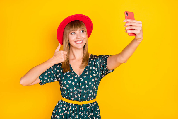 Retrato de encantadora chica alegre haciendo selfie mostrando pulgar anuncio de acuerdo aislado sobre fondo de color amarillo brillante - Foto, imagen
