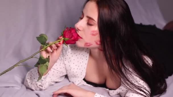 σέξι μελαχρινή γυναίκα με φιλιά, σημάδια κραγιόν στο πρόσωπο και το λαιμό της, με κόκκινο τριαντάφυλλο. Φιλενάδα, ραντεβού, επανασύνδεση. αντίγραφο χώρου - Πλάνα, βίντεο
