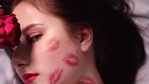 sexy donna bruna con baci, segni di rossetto sul viso e sul collo, con rosa rossa. fidanzata, appuntamento, relazione. copia spazio - Filmati, video