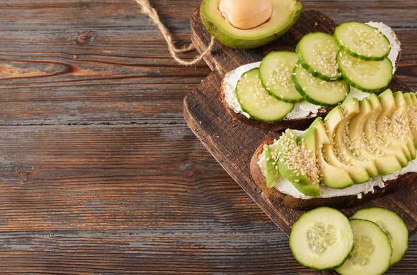 sandwiches with soft cheese, cucumber and avocado on a wooden background - 写真・画像