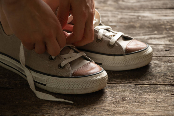 female legs in brown sneakers stand on the wooden floor at home, sports shoes - Photo, Image