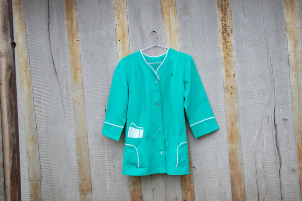 vieux costume médical accroché à un cintre sur le mur dans la rue en Ukraine, uniforme d'infirmière - Photo, image