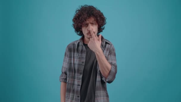 Young irritated hipster, points his finger in the face and shows the bad sign, in the studio on a turquoise background. The concept of peoples lifestyle - Footage, Video