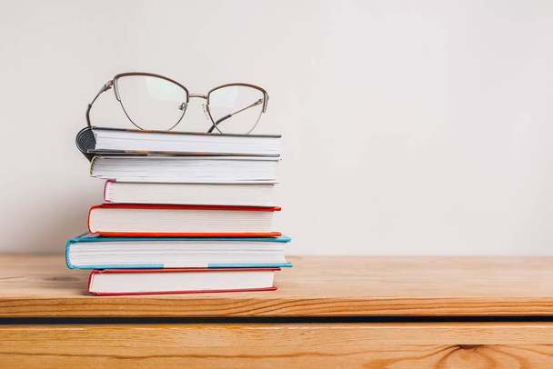 A stack of books and glasses on the table. Mock up with education and reading concept. Literature for learning, development and joy - Foto, Imagen