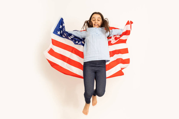 Schattig klein meisje en USA vlag op de achtergrond - Foto, afbeelding
