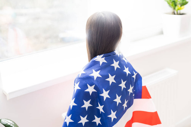 Όμορφο πατριωτικό κοριτσάκι με την αμερικανική σημαία στα απλωμένα χέρια της - Φωτογραφία, εικόνα