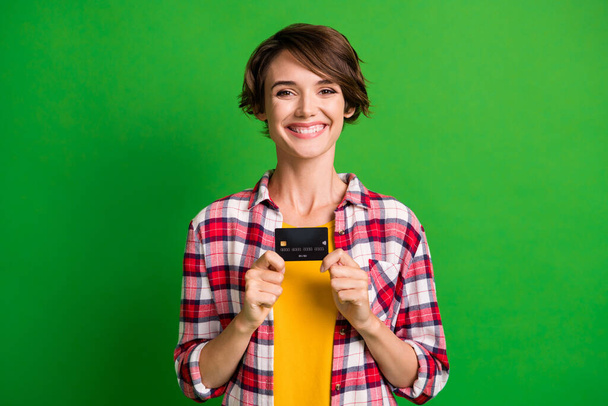 Photo of optimistic pretty short hairdo girl hold card wear orange cloth isolated over vivid green color background - Φωτογραφία, εικόνα