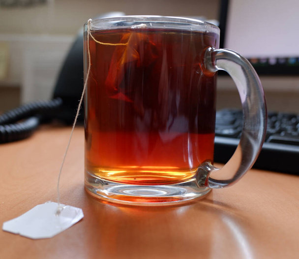 A teafiltert egy bögrében főzték az irodai asztalon, a munka szünet koncepciója szerint. másolás helye. - Fotó, kép