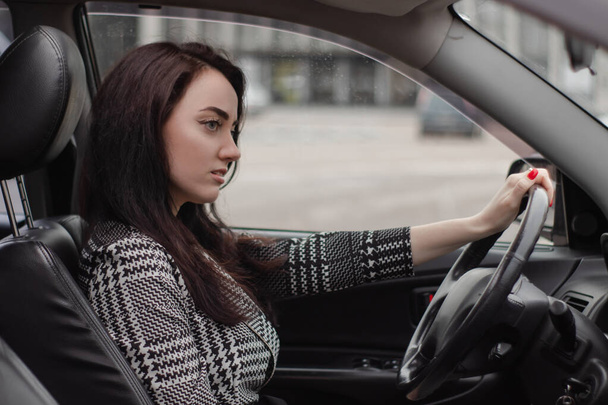 portrét atraktivní brunetky ženy v kostkovaných šatech v luxusním autě. dáma v autě - Fotografie, Obrázek