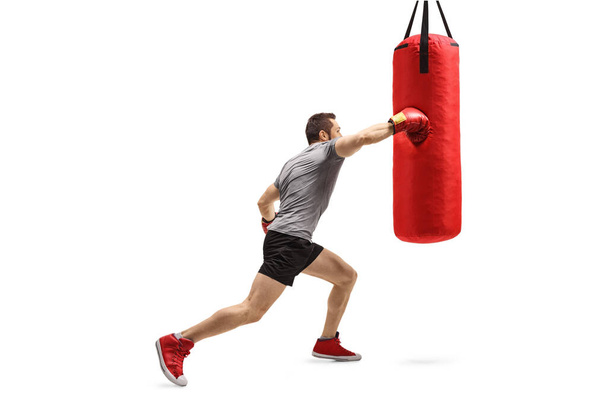 Strong man exercising and punching a boxing bag isolated on white background - Фото, зображення