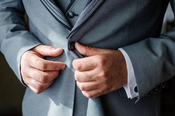 The man fasten a button on his jacket. The groom fasten a button on his jacket - Photo, Image
