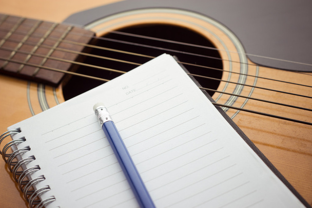 Cuaderno y lápiz en la guitarra
 - Foto, imagen