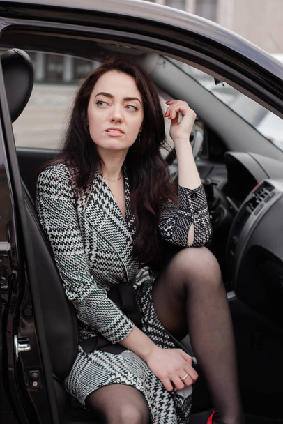retrato de mulher morena fabulosa atraente vestindo vestido xadrez em um carro lux. senhora no automóvel - Foto, Imagem