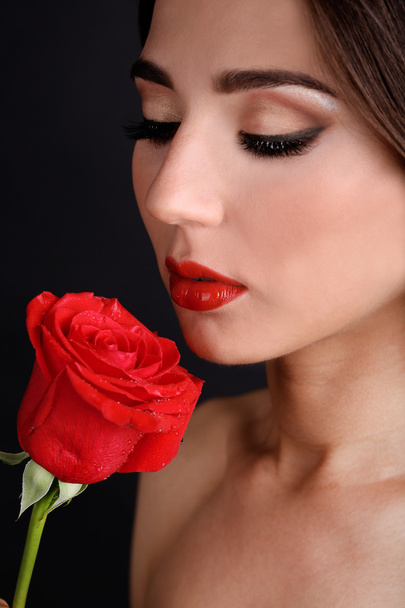 Girl with red lips and rose on dark background - Фото, изображение