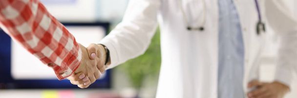 Lekarz ze stetoskopem wokół szyi podający pacjentom dłoń w klinice zbliżenie - Zdjęcie, obraz