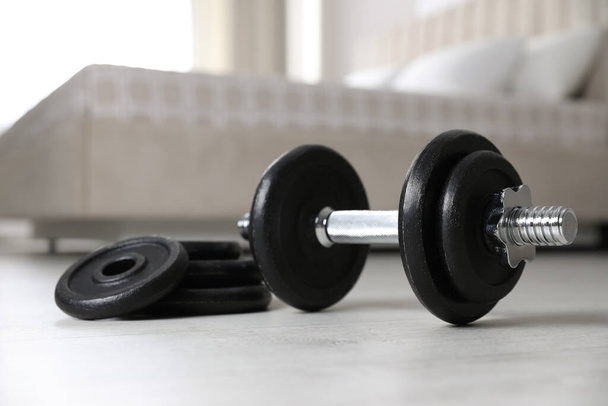 Steel dumbbell and weight plates on floor indoors. Fitness at home - Foto, Imagem