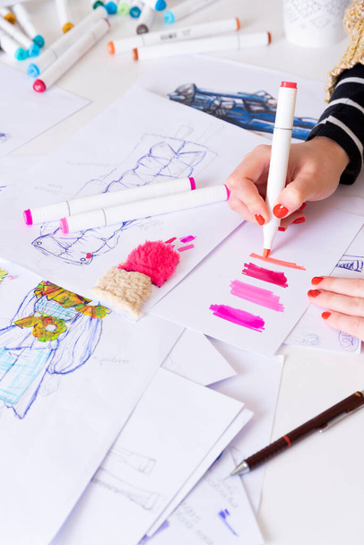mladá bruneta žena navrhuje módní šaty kresba s barevnými tužkami. Různé barevné módní kresby a náčrtky - Fotografie, Obrázek