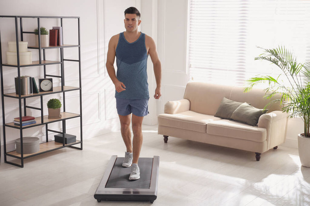 Sporty man training on walking treadmill at home - Foto, imagen