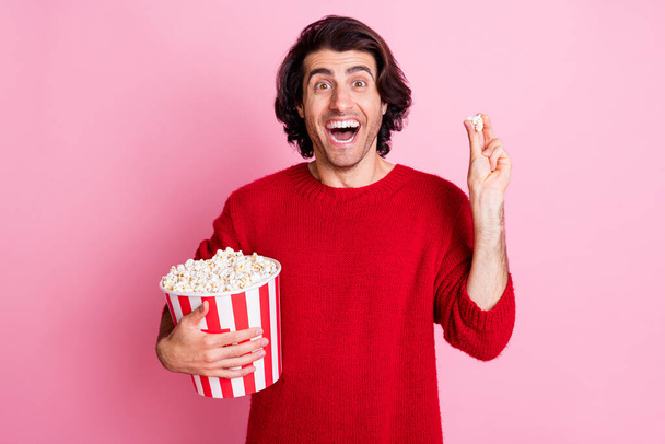 Photo portrait of cheerful happy male brunette watching tv eating popcorn isolated on pastel pink color background - Φωτογραφία, εικόνα