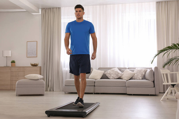 Sporty man training on walking treadmill at home - Fotoğraf, Görsel