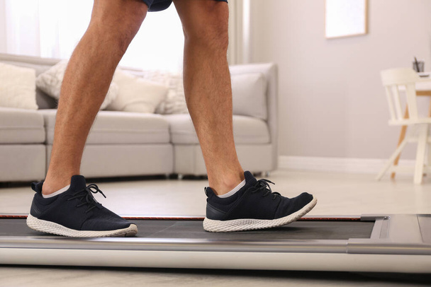 Man training on walking treadmill at home, closeup - 写真・画像