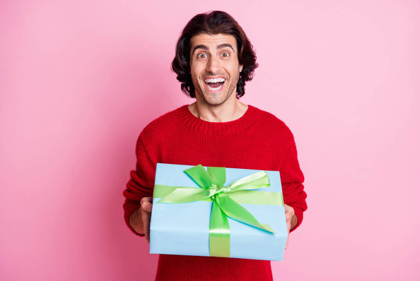 Photo portrait of excited screaming guy holding gift box isolated on pastel pink colored background - Foto, Imagen