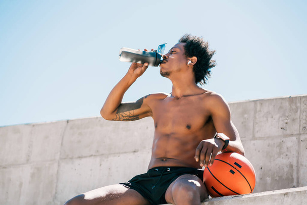 Athletic man drinking water after work out outdoors. - 写真・画像