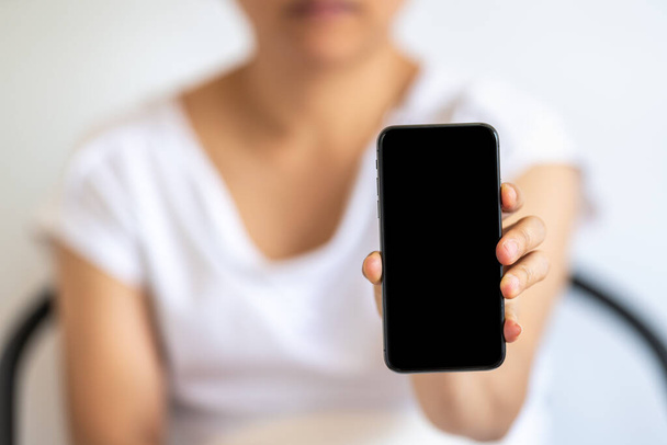 Primo piano di donna mano in mano e mostrare vuoto isolato schermo nero smartphone cellulare. - Foto, immagini
