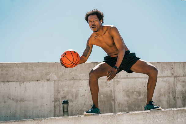 Afro athlete man playing basketball outdoors. - 写真・画像